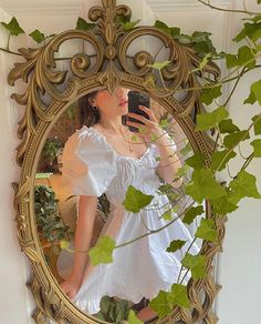 a woman in a white dress is taking a selfie with her cell phone while looking into the mirror