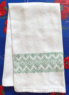 two white towels with green and red designs on them