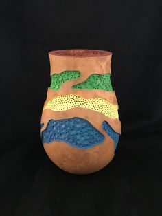 a ceramic vase with different colored designs on it's sides and the bottom part of its body