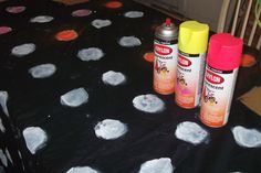 two spray cans sitting on top of a table covered in polka dot paper and paint