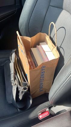 a brown paper bag filled with books sitting in the back seat of a car next to a pile of folders