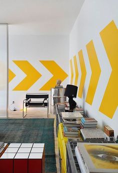 a living room with yellow arrows painted on the wall and furniture in the foreground