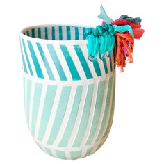 a blue and white striped vase with tassels on the top, sitting in front of a white background