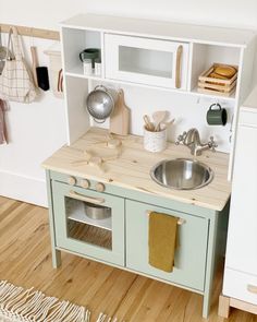 a wooden play kitchen with sink and cupboards