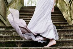 a woman in a white dress is walking down some stairs