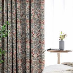 the curtains in this bedroom are made up of floral print, with a plant next to it