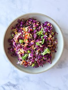 a white bowl filled with coleslaw on top of a marble counter