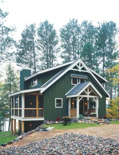 a green house sitting on top of a hill next to a forest filled with trees