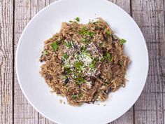 a white plate topped with rice and meat covered in parmesan sprinkles