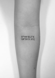 a black and white photo of a person's arm with a coordinates tattoo on it