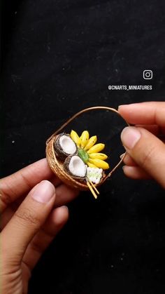 a person is holding a miniature basket with flowers in it and coconuts on the inside