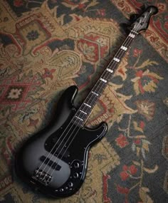 a black bass guitar laying on top of a carpet