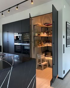 an open kitchen with black cabinets and marble counter tops