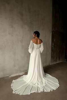 a woman in a white wedding dress is looking off into the distance with her back to the camera