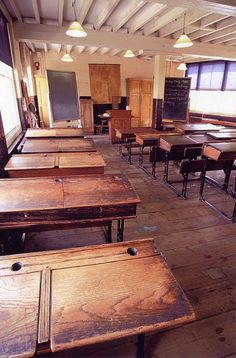 an empty classroom with wooden desks and chalkboard