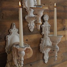 two candles are lit on the wall next to some sconces