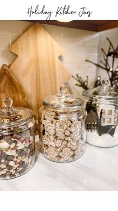 three glass jars filled with nuts on top of a counter