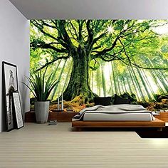 a bedroom with a large tree mural on the wall and bed in the foreground