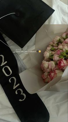 a graduation cap and bouquet of flowers on a white sheet