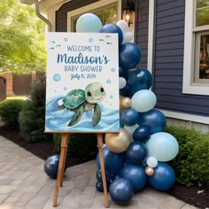 a welcome sign for a baby shower with blue and gold balloons in the shape of a turtle