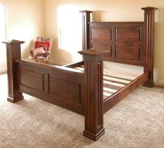 a bed with wooden headboard and foot board on carpeted flooring in an empty room