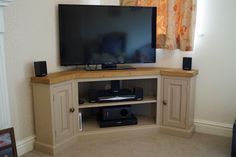 a flat screen tv sitting on top of a wooden entertainment center next to a window