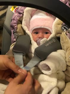 a baby in a car seat being held by someone's hand with a pair of scissors