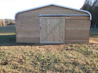 a small wooden shed sitting on top of a grass covered field