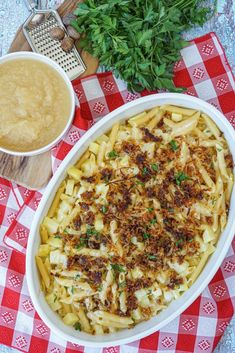 a large casserole dish on a red and white checkered tablecloth next to a bowl of gravy