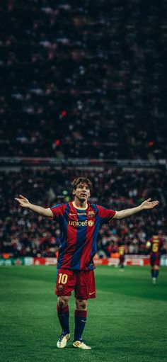 a man standing on top of a soccer field holding his arms out in the air