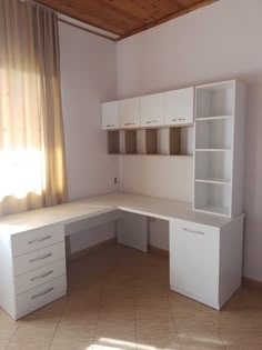 an empty room with a desk and cabinets in the corner, next to a window