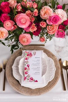 a place setting with pink and red flowers