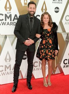 two people standing on a red carpet at an awards event