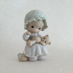 a figurine of a girl holding a teddy bear