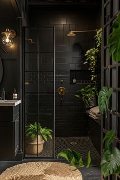 a bathroom with black tile and plants in the corner, along with a round rug on the floor