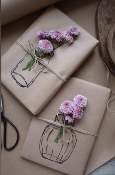 three packages with flowers tied to them sitting on top of a table next to scissors