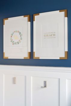 two framed pictures on the wall above a white door with gold trimmings and blue walls