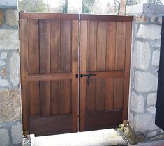 two wooden doors are open in front of a stone wall