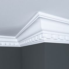 the corner of a room with a white crown molding on the ceiling and gray walls