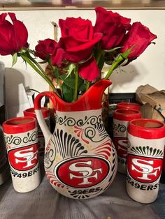 a vase with roses in it sitting on a table next to cups and a toaster