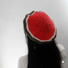 a woman with long black hair wearing a red and green crocheted hat on top of her head