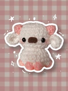 a crocheted white teddy bear sitting on top of a checkered table cloth