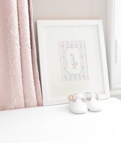 a pair of white shoes sitting on top of a table next to a framed picture