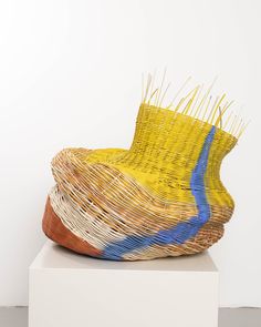 a yellow and blue basket sitting on top of a white pedestal