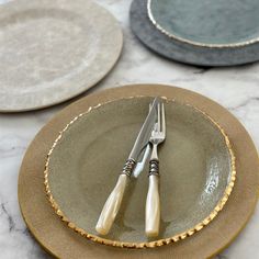 three plates with silverware on them sitting on a marble counter top next to each other