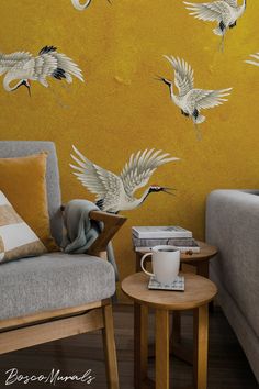 two chairs and a table in front of a wall with birds painted on it