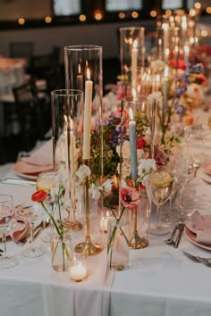 the table is set with candles, flowers and wine glasses for an elegant wedding reception