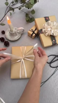 a person is wrapping presents on a table with candles and other items around it,