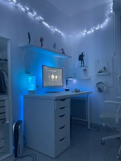 a white desk topped with a computer monitor next to a blue light filled wall behind it