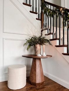 a wooden table sitting under a banister next to a stair case with plants on it